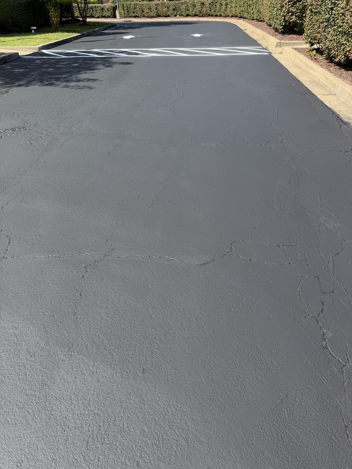 A freshly sealcoated parking lot entrance with new white arrows and stripes