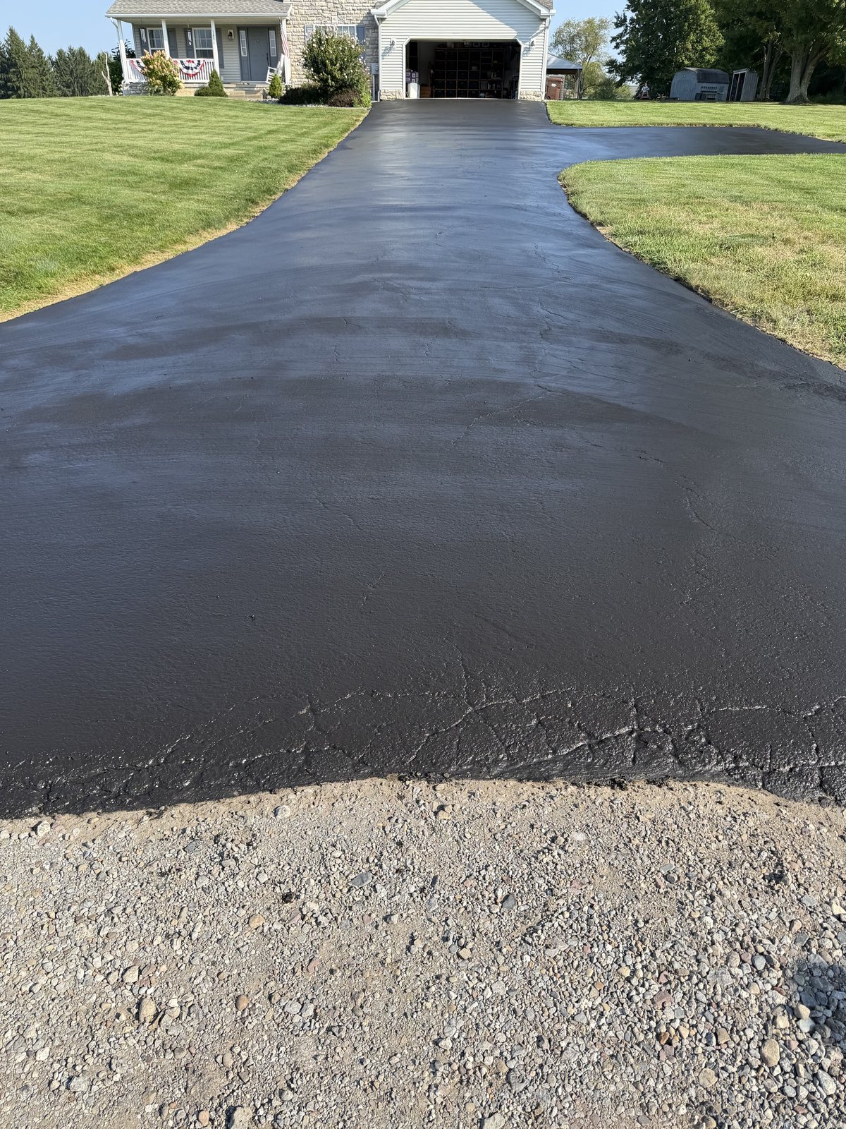 A long residential driveway freshly sealcoated by Hamilton Driveway Defense