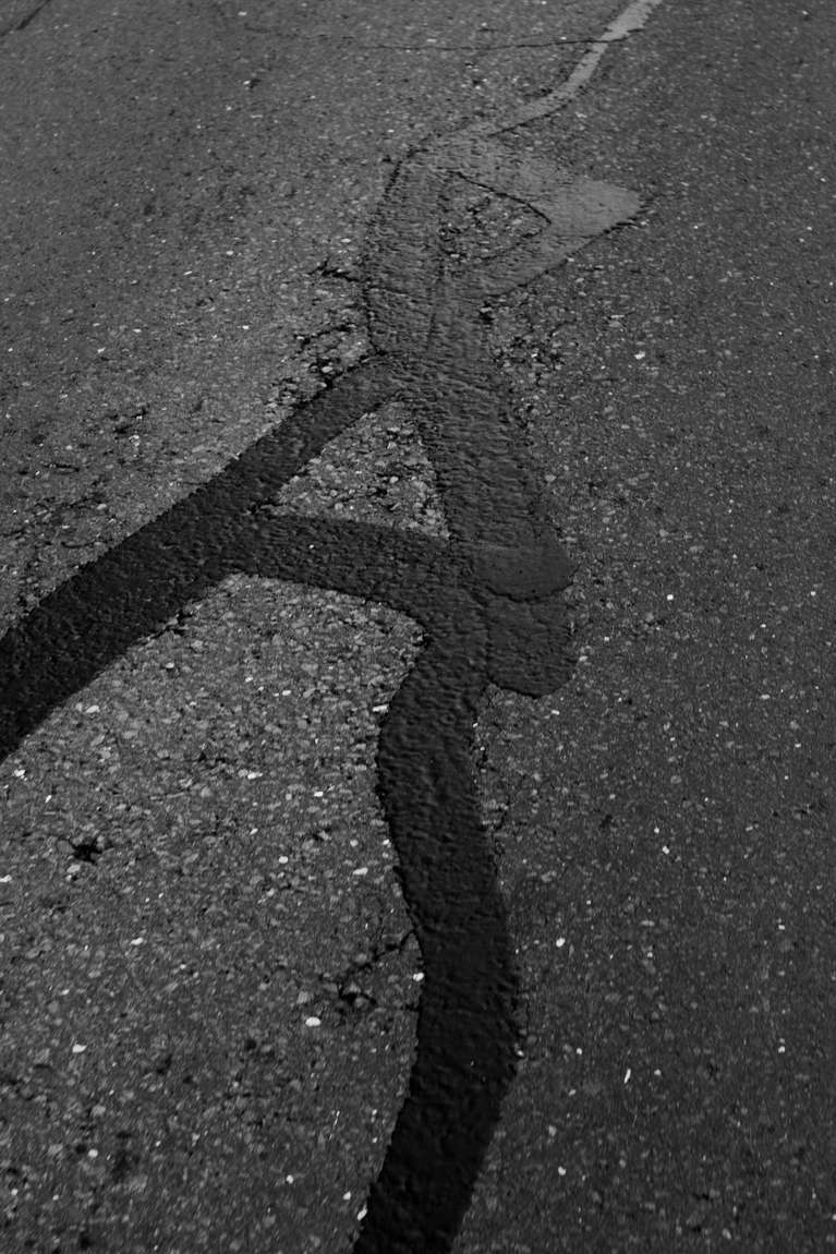 A crack in asphalt filled with dark sealant
